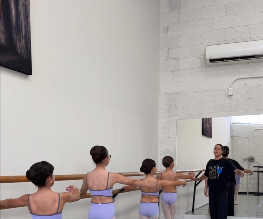 Alumnas en la barra con la maestra al fondo del salón.